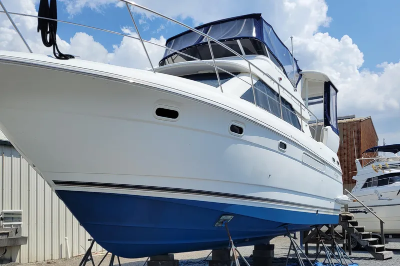 Slide: The Image of 2001 Cruisers 3750 yacht on stands, blue hull, white upper deck, clear sky background. - 4