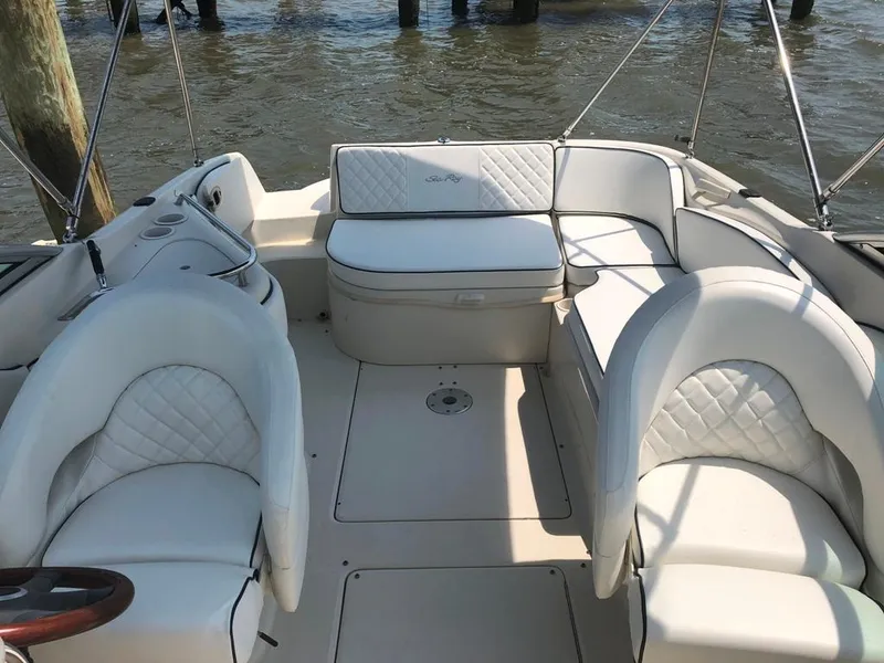 Slide: The Image of 2004 Sea Ray 240 Sundeck interior with white seating, docked by water. - 10
