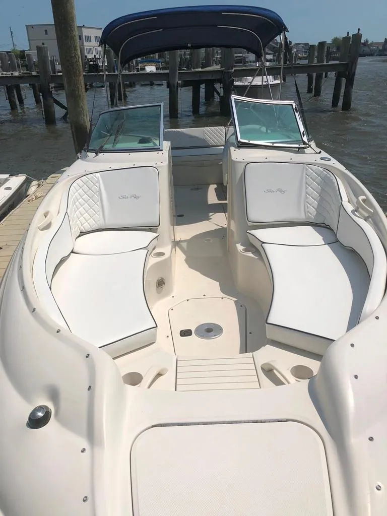 Slide: The Image of 2004 Sea Ray 240 Sundeck boat with spacious seating and canopy, docked by the water. - 11