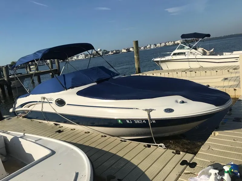 Slide: The Image of 2004 Sea Ray 240 Sundeck boat docked by the water with blue canopy. - 6