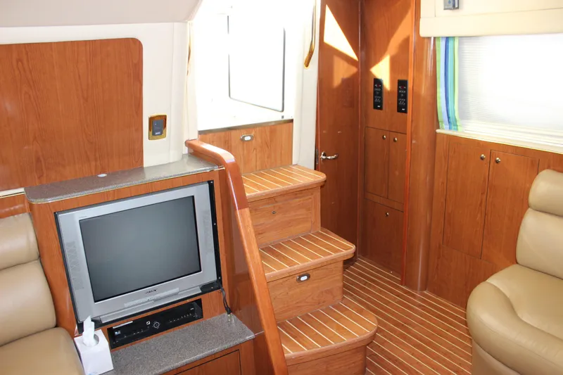 Slide: The Image of Interior of 2002 Sea Ray 480 Motor Yacht with TV, wooden stairs, and seating. - 39