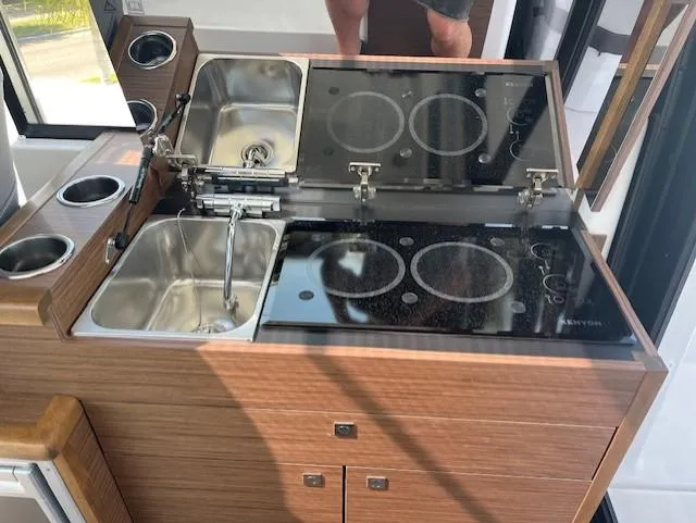 Slide: The Image of 2024 Jeanneau NC Weekender 895 kitchen with dual sinks and electric stove. - 12