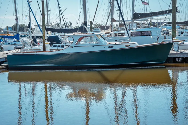 Slide: The Image of 2000 Hinckley Picnic Boat Classic docked in a marina, reflecting on calm water. - 1