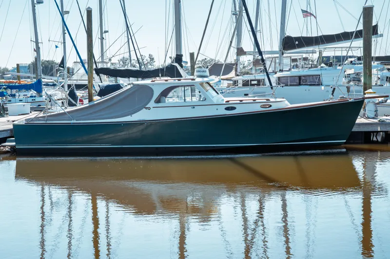Slide: The Image of 2000 Hinckley Picnic Boat Classic docked in a marina, reflecting on calm water. - 10