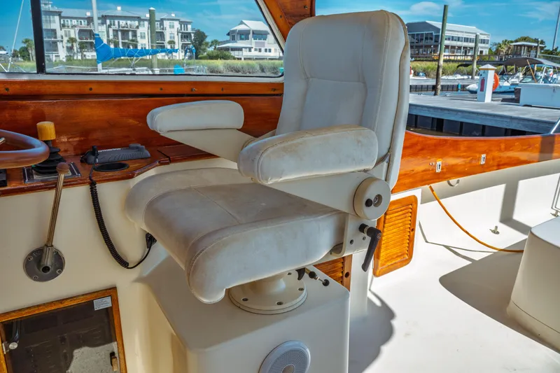 Slide: The Image of Captain's chair on 2000 Hinckley Picnic Boat Classic, with wooden dashboard and marina view. - 25