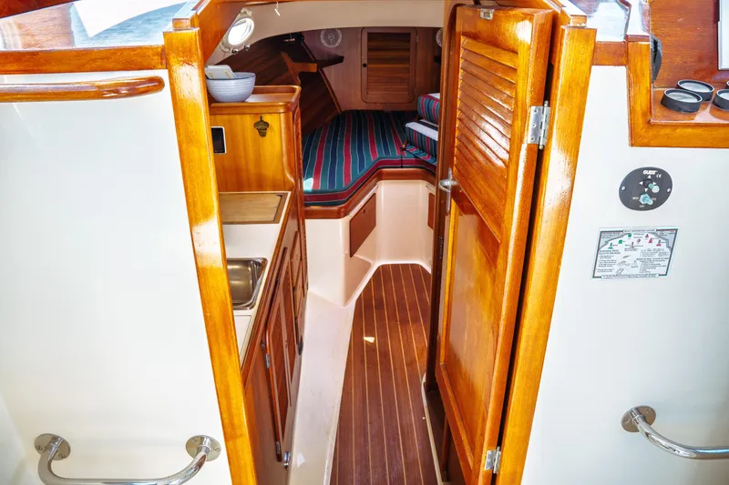 Slide: The Image of Interior of 2000 Hinckley Picnic Boat Classic with wood finishes and striped bedding. - 41