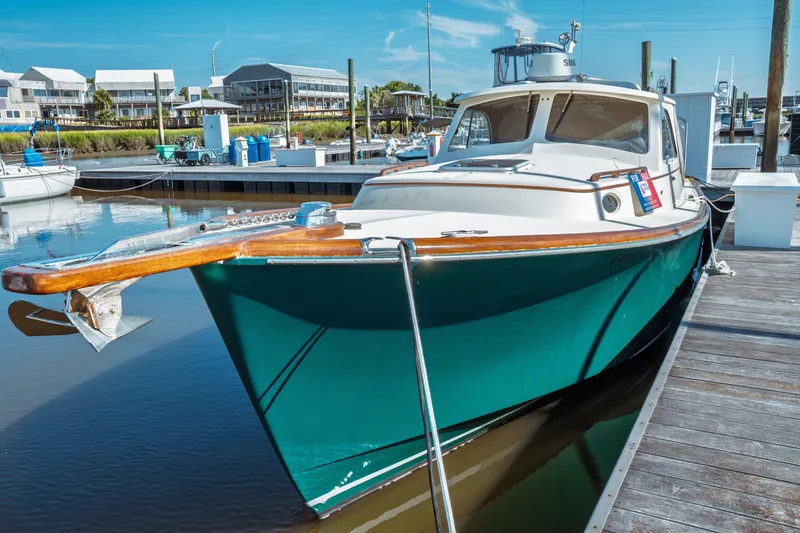 Slide: The Image of 2000 Hinckley Picnic Boat Classic docked at marina, featuring sleek design and vibrant teal hull. - 8