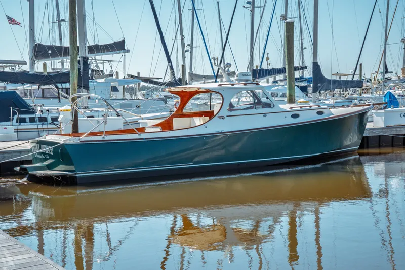 The Image of 2000 Hinckley Picnic Boat Classic docked at a marina, surrounded by sailboats. - 0
