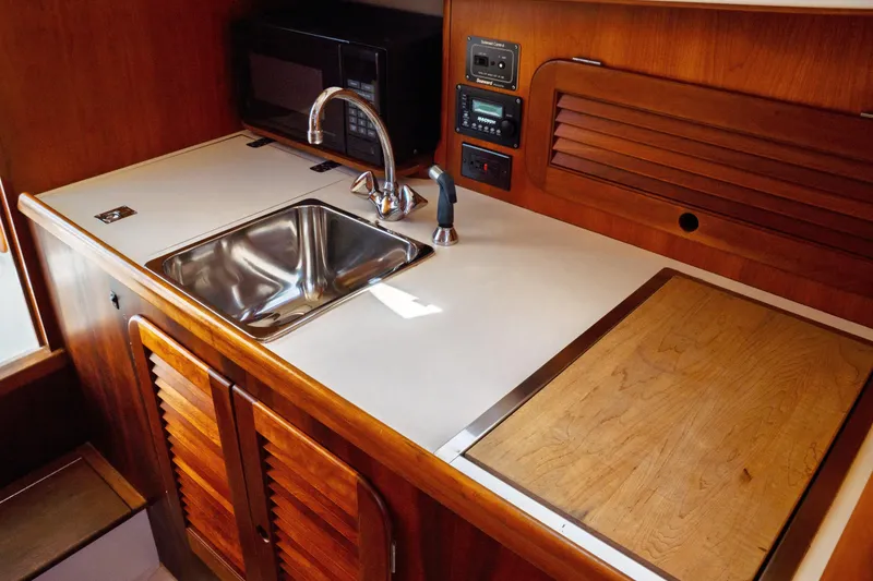 Slide: The Image of Hinckley Picnic Boat Classic 2000 interior galley with sink, microwave, and wooden cabinetry. - 43