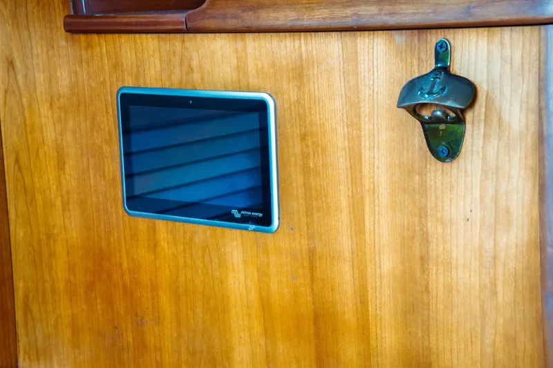 Slide: The Image of Wooden panel with a digital display and metal bottle opener on a 2000 Hinckley Picnic Boat Classic. - 50