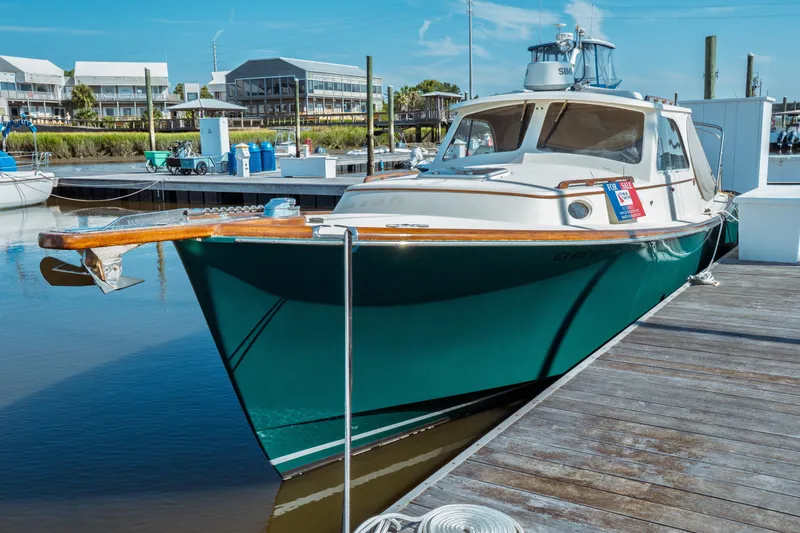 Slide: The Image of 2000 Hinckley Picnic Boat Classic docked, for sale sign visible, marina background. - 7