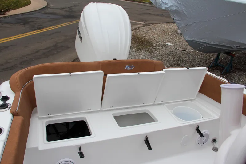 Slide: The Image of 2024 Sea Hunt Ultra 234 boat with open storage compartments and outboard motor. - 11