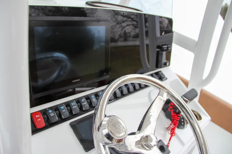Slide: The Image of 2024 Sea Hunt Ultra 234 boat dashboard with steering wheel and electronic controls. - 25