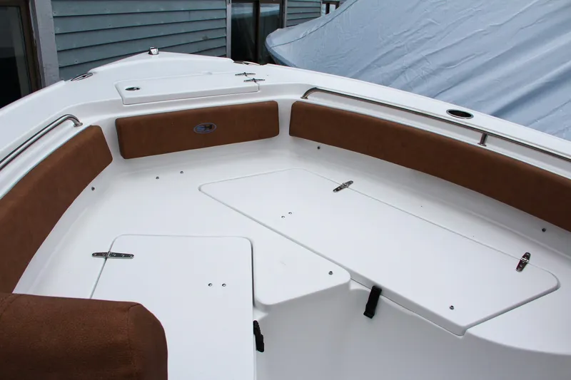 Slide: The Image of 2024 Sea Hunt Ultra 234 boat interior with brown cushioned seating and storage compartments. - 34