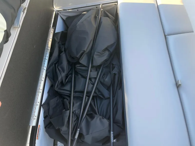 Slide: The Image of 2024 Starcraft SLS3 boat storage compartment with black cover and poles. - 13