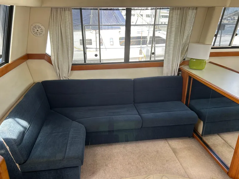 Slide: The Image of Interior of 1994 Bayliner 4587 Motoryacht with blue L-shaped sofa and large windows. - 4