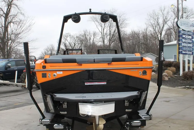 Slide: The Image of 2024 Axis T235 boat, rear view, orange and black design, parked outdoors. - 5