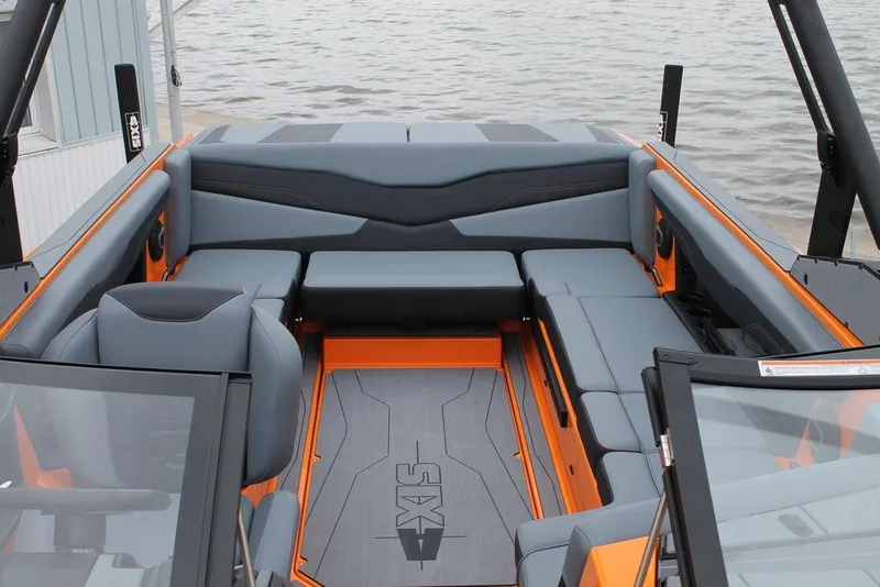 Slide: The Image of 2024 Axis T235 boat interior with gray and orange seating, docked by water. - 8