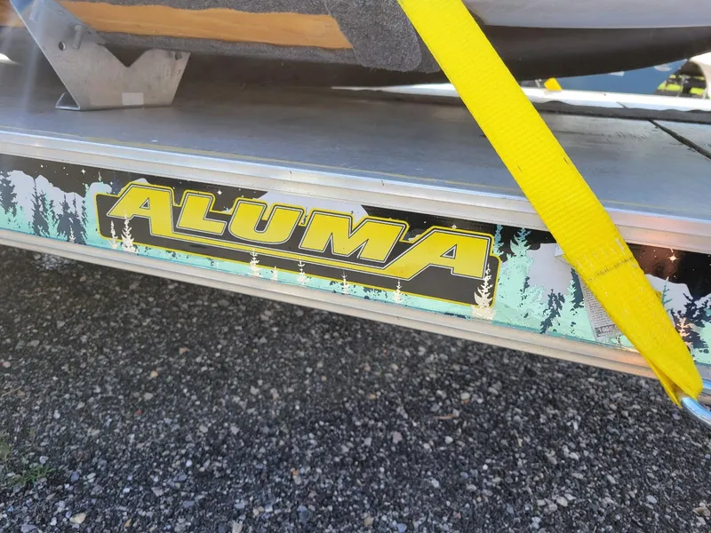 Slide: The Image of Aluma trailer with yellow strap securing Sea Eagle inflatable boat, gravel ground. - 5