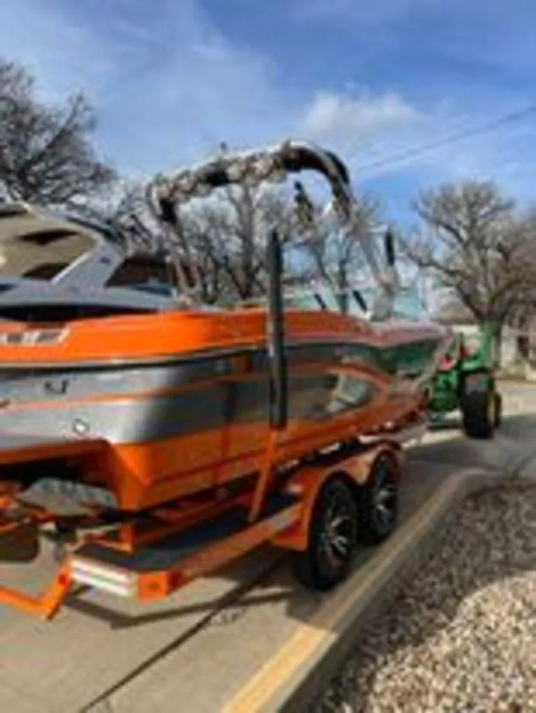 Slide: The Image of 2014 MasterCraft X30 boat on trailer, orange and gray, parked outdoors. - 2