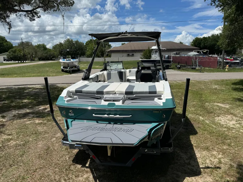 Slide: The Image of 2024 Malibu LX-R boat, rear view, parked on grass under a sunny sky. - 34