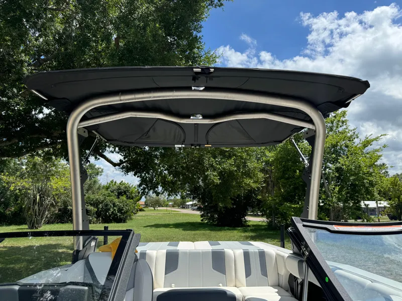 Slide: The Image of 2024 Malibu LX-R boat with canopy and seating, parked outdoors. - 35