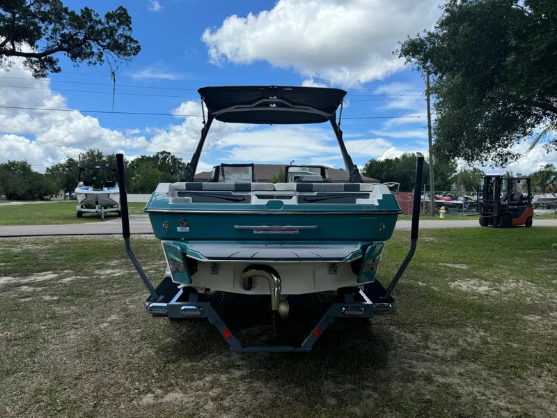 Slide: The Image of 2024 Malibu LX-R boat, rear view, parked on grass under a partly cloudy sky. - 38