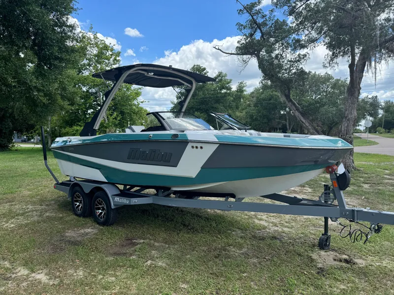 Slide: The Image of 2024 Malibu LX-R boat on a trailer in a grassy area with trees. - 4