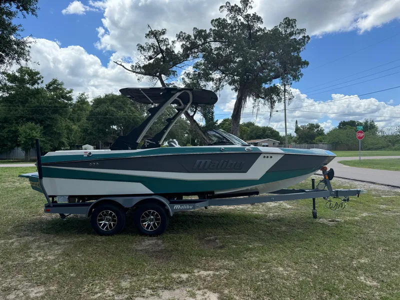 Slide: The Image of 2024 Malibu LX-R boat on a trailer, parked on grass under a partly cloudy sky. - 5