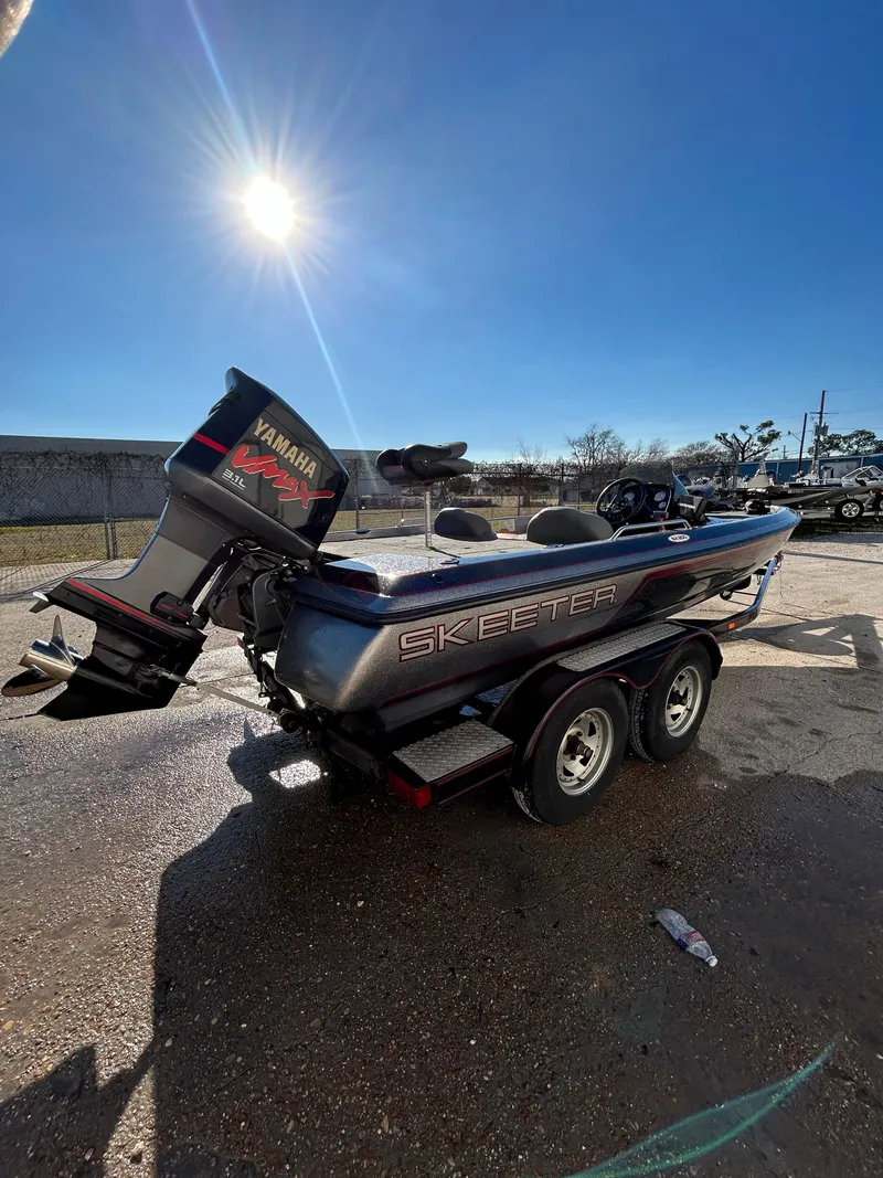 Slide: The Image of 2003 Skeeter SX 200 fishing boat with red and gray seats in a parking lot. - 13