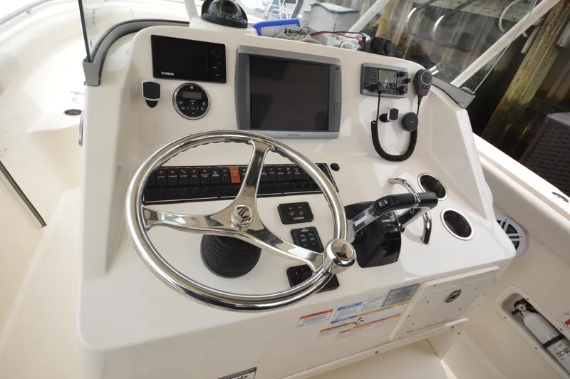 Slide: The Image of Control panel of a 2012 Pursuit 280 boat with steering wheel and navigation equipment. - 12