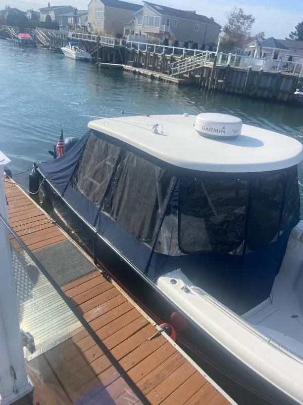 Slide: The Image of 2012 Pursuit 280 boat docked in a marina with waterfront homes in the background. - 2