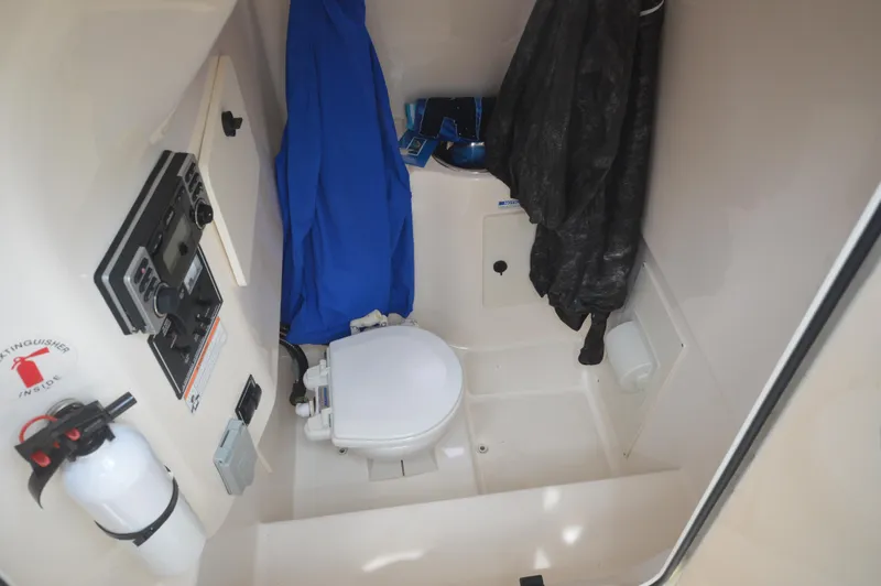 Slide: The Image of 2012 Pursuit 280 boat interior with toilet, fire extinguisher, and hanging jackets. - 23