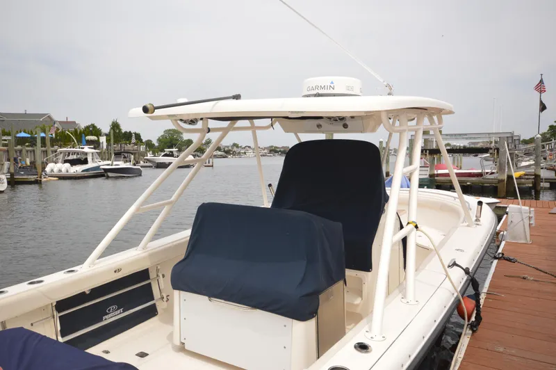Slide: The Image of 2012 Pursuit 280 boat docked at a marina, featuring a covered helm and seating. - 29