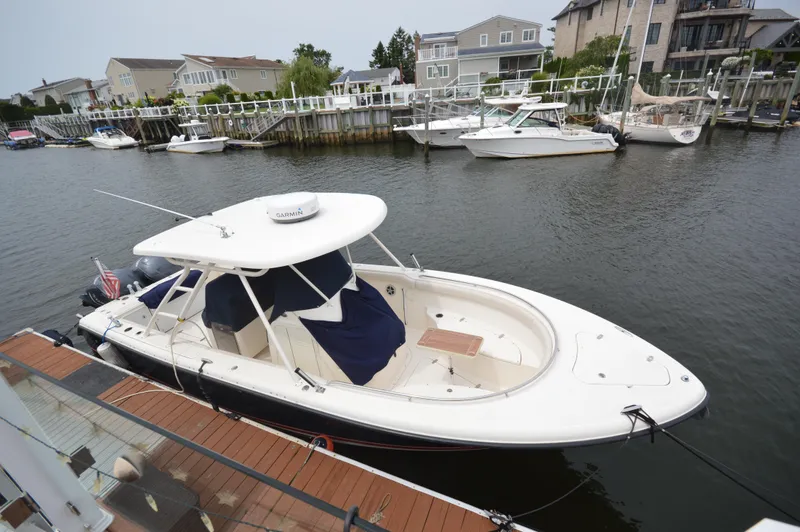 Slide: The Image of 2012 Pursuit 280 boat docked in a marina with waterfront homes in the background. - 5