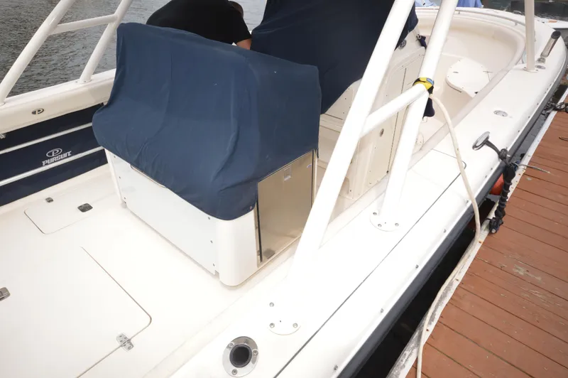 Slide: The Image of 2012 Pursuit 280 boat docked, covered seating, white deck, and stainless steel fixtures. - 27