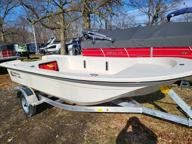 Slide: The Image of 2024 Carolina Skiff E16 JVX TH boat on a trailer in a wooded area. - 17