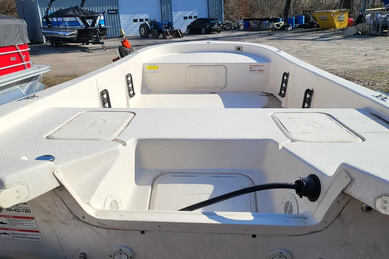 Slide: The Image of 2024 Carolina Skiff E16 JVX TH boat interior, white deck, storage compartments, and seating. - 8