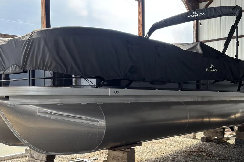 Slide: The Image of 2024 Veranda Relax VR25VLC pontoon boat covered in black tarp, stored indoors. - 7
