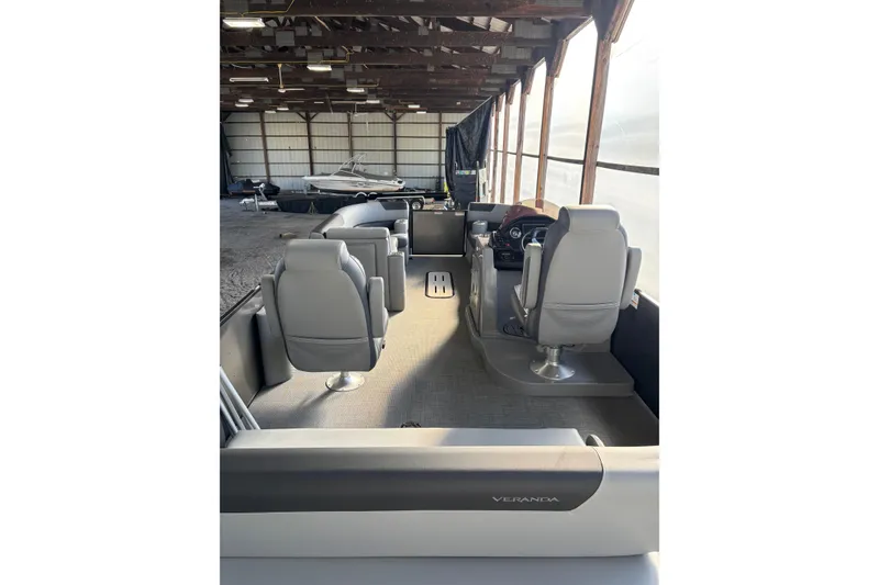 Slide: The Image of 2024 Veranda Relax VR25VLC pontoon boat interior with seating and steering console in storage. - 8