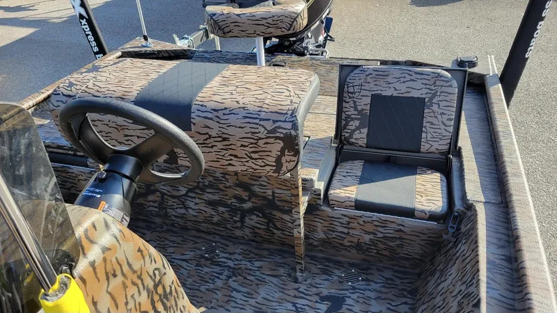 Slide: The Image of 2025 Xpress XP20CC center console boat interior with camouflage seating and steering wheel. - 6