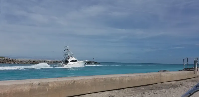 Slide: The Image of 1986 Post Sportfisher boat cruising on clear blue ocean near a concrete seawall. - 1