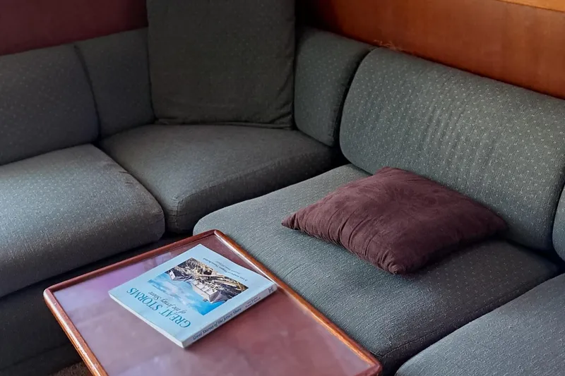 Slide: The Image of 1986 Post Sportfisher interior with gray sofa, brown pillow, and table with a book. - 34