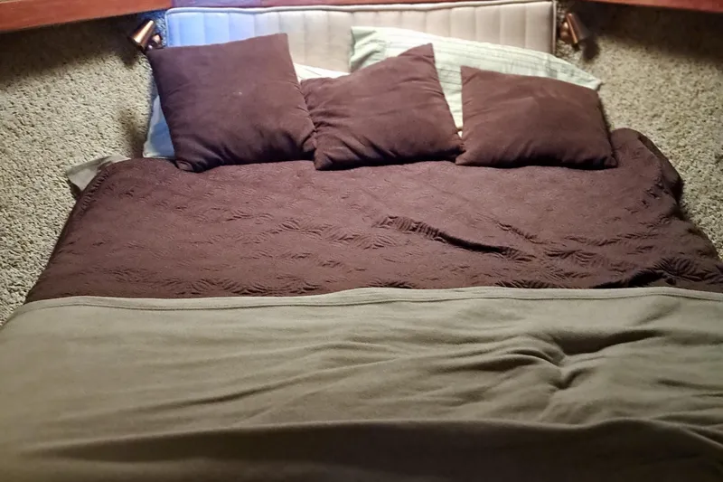 Slide: The Image of Bed in the cabin of a 1986 Post Sportfisher boat with brown pillows and blankets. - 31