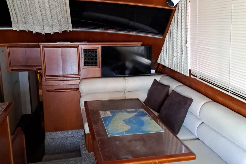 Slide: The Image of 1986 Post Sportfisher boat interior with dining area, map table, and beige seating. - 43
