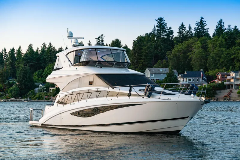Slide: The Image of 2012 Meridian 541 Sedan yacht on a serene lake with forested shoreline. - 2