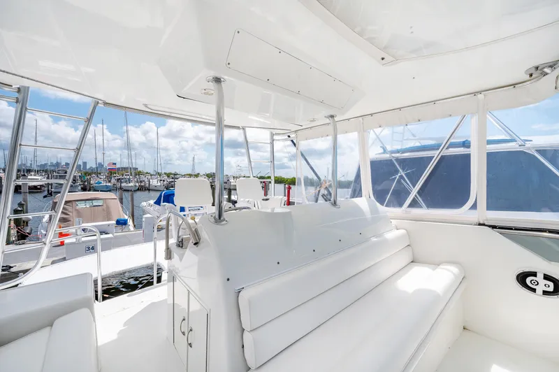 Slide: The Image of Interior view of a 1992 Hatteras 50 Convertible yacht with white seating and marina backdrop. - 14