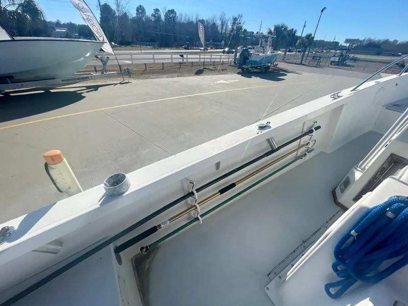 Slide: The Image of 1980 Robalo 2380 boat deck with fishing rod holders and blue rope. - 11