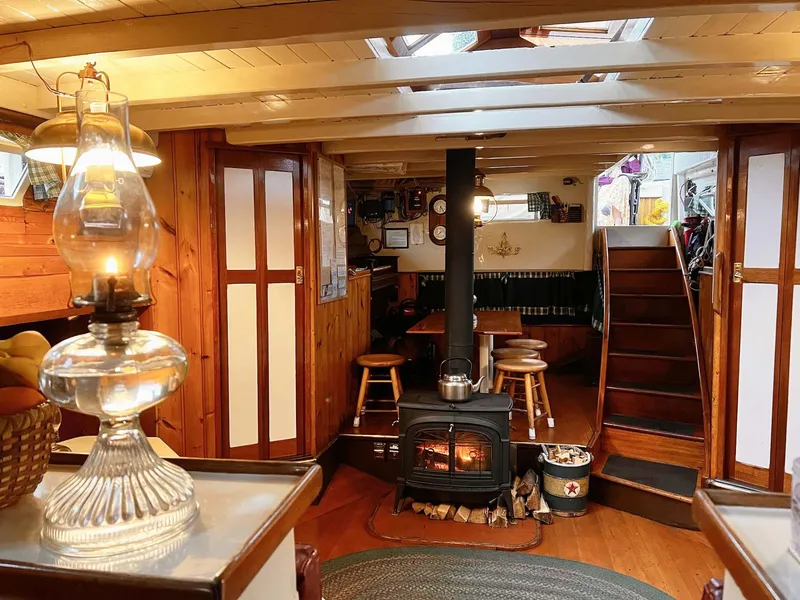Slide: The Image of Interior of 1962 Gamage Coastal Gaff Rigged Schooner with cozy wood stove and vintage decor. - 28