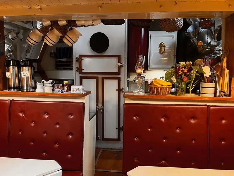 Slide: The Image of Interior of 1962 Gamage Coastal Gaff Rigged Schooner with cozy dining area and vintage decor. - 30